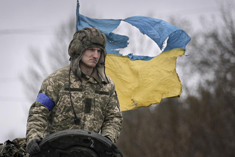 Un militar ucraniano tiene como telón de fondo la bandera de su país mientras está parado en un tanque, en las afueras de Kiev, Ucrania, el sábado 2 de abril de 2022. A medida que las fuerzas rusas se retiran de la región de la capital de Ucrania, las tropas en retirada crean una situación "catastrófica" para los civiles al abandonar minas alrededor de casas, equipos abandonados e "incluso los cuerpos de los muertos", advirtió el sábado el presidente Volodymyr Zelenskyy. (AP Photo/Vadim Ghirda)