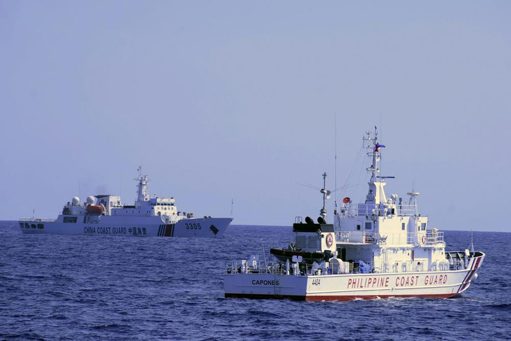 In this photo provided by the Philippine Coast Guard, a Chinese Coast Guard ship sails near a Philippine Coast Guard vessel during its patrol at Bajo de Masinloc, 124 nautical miles west of Zambales province northwestern Philippines on March 2, 2022. Chinese coast guard ships have maneuvered dangerously close to Philippine coast guard ships at least four times since last year near a disputed shoal that increased the risks of collision and violated international safety regulations, the Philippine coast guard said Sunday. (Philippine Coast Guard via AP)