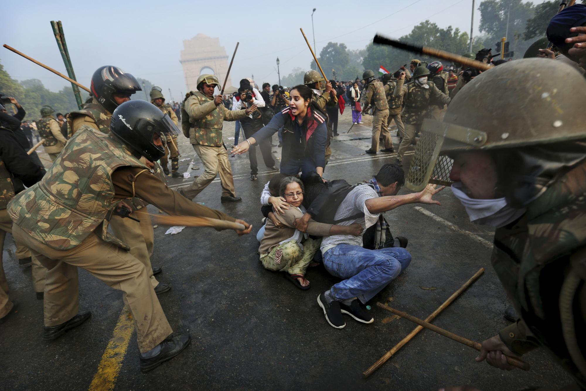 FILE - Protesters shield themselves as police beat them with sticks during a violent demonstration near the India Gate against a gang rape and brutal beating of a 23-year-old student on a bus last week, in New Delhi, India Dec. 23, 2012. The attack sparked widespread protests across the country, leading to tougher laws against rape. (AP Photo/Kevin Frayer, File)