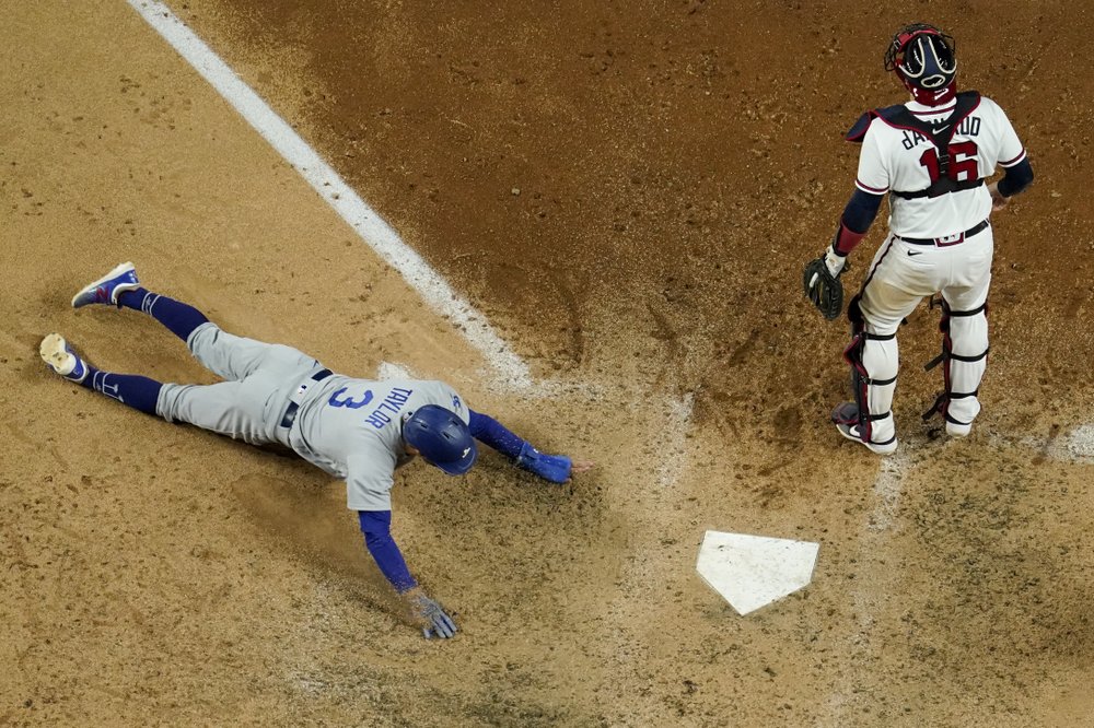 Chris Taylor de Los Angeles Dodgers supera al receptor de los Bravos de Atlanta, Travis d'Arnaud, con un hit de Mookie Betts durante la séptima entrada en el Juego 5 de una Serie de Campeonato de la Liga Nacional de MLB el viernes 16 de octubre de 2020.