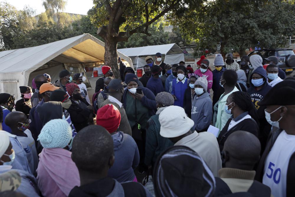 People try to figure out what to do after being turned away at a government hospital while seeking to be vaccinated against COVID-19 in Harare, Zimbabwe on Saturday, July, 10, 2021. About 6% of the population in Zimbabwe has received one dose of the coronavirus vaccine amid a surge of the easier to spread delta variant, first seen in India. Many millions of people vulnerable to COVID-19, including the elderly and those with underlying medical problems, are struggling to get immunized as government officials introduce more restrictive measures. (AP Photo/Tsvangirayi Mukwazhi)