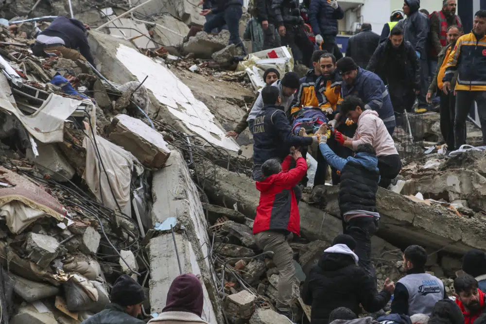 Personas y equipos de emergencia rescatan a una persona en una camilla de un edificio derrumbado en Adana, Turquía, el lunes 6 de febrero de 2023. Un poderoso terremoto derribó varios edificios en el sureste de Turquía y Siria y se temen muchas víctimas.  (Agencia IHA vía AP)