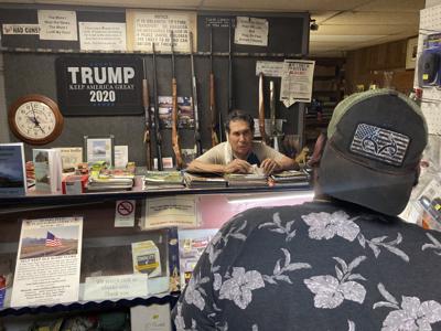 Jesús "Chuy" Aguirre, propietario de una tienda de armas, de frente a la cámara, atiende al cliente Ángel Zacarías, de espaldas en primer plano, el jueves 26 de agosto de 2021, en Chuy's Gun Shop, en El Paso, Texas, en un momento en que crece la expectativa con respecto a una nueva ley del estado que relaja las restricciones sobre la tenencia de armas de fuego. (AP Foto/Morgan Lee)