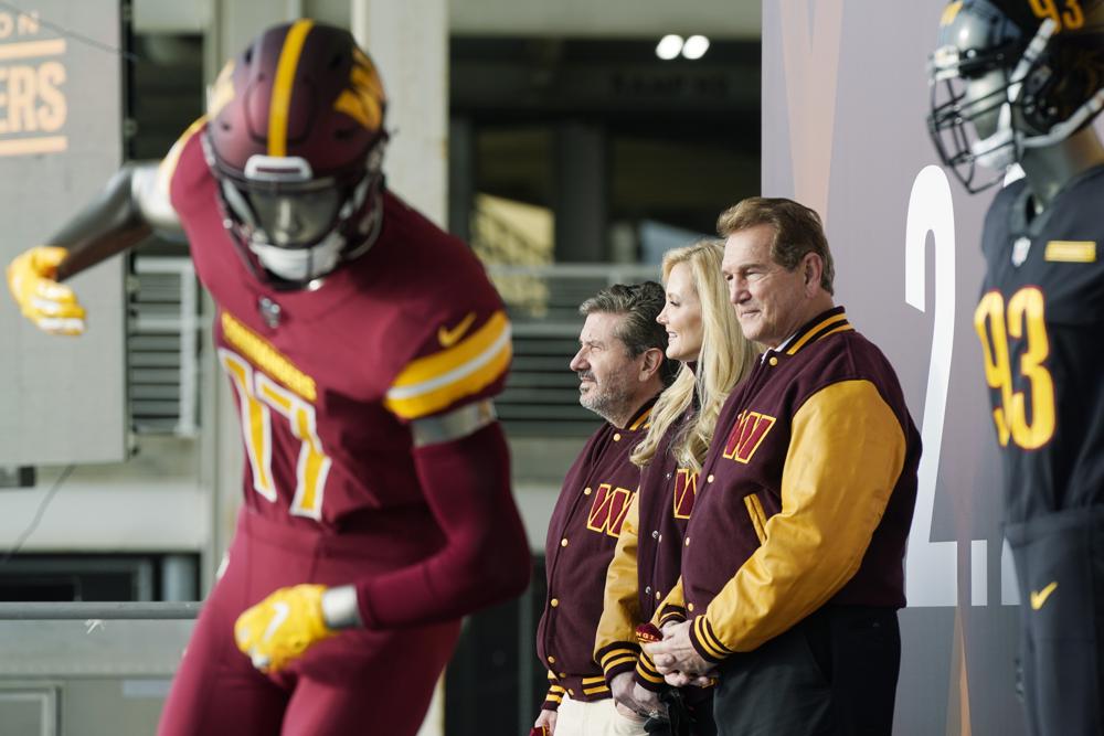 Dan and Tanya Snyder, co-owners and co-CEOs of the Washington Commanders and and former quarterback Joe Theismann, right, unveil their NFL football team's new identity, Wednesday, Feb. 2, 2022, in Landover, Md. The new name comes 18 months after the once-storied franchise dropped its old moniker following decades of criticism that it was offensive to Native Americans. (AP Photo/Patrick Semansky)