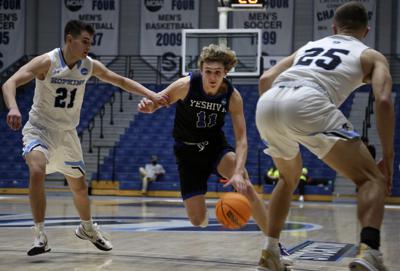 Ryan Turell (11) de la Universidad Yeshiva regatea la pelota por la cancha mientras es defendido por Carson James (21) y Lincoln Yeutter (25) de la Universidad Johns Hopkins en la primera ronda del torneo de baloncesto de la División III de la NCAA, en Galloway Township, Nueva Jersey, el viernes 4 de marzo de 2022. Los Macabeos de la Yeshivá perdieron ante los Azulejos, 63-59 en el Centro Deportivo de la Universidad de Stockton. (AP Photo/Jessie Wardarski)