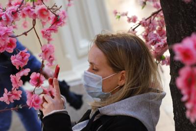 Una mujer con mascarilla para combatir los contagios de coronavirus hace fotos de flores en los grandes almacenes GUM cerca de la Plaza Roja de Moscú, Rusia, el jueves 10 de junio de 2021. (AP Foto/Alexander Zemlianichenko)