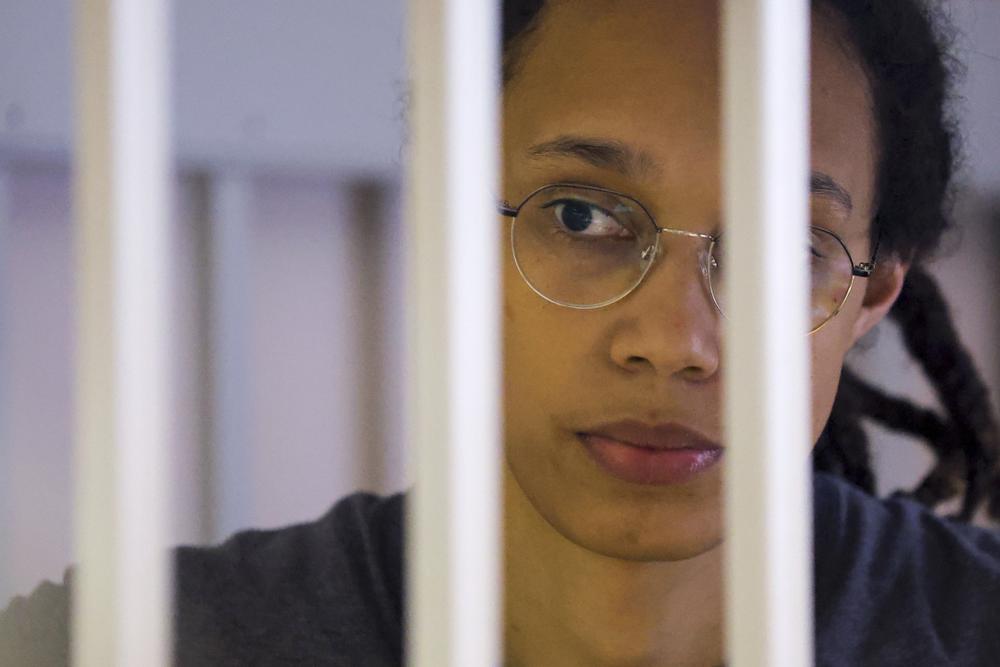 FILE - US Basketball player Brittney Griner looks through bars as she listens to the verdict standing in a cage in a courtroom in Khimki, outside Moscow, Russia, Thursday, Aug. 4, 2022. Lawyers for American basketball star Brittney Griner on Monday, Aug. 15, 2022 filed an appeal of her nine-year Russian prison sentence for drugs possession. Griner, a center for the Phoenix Mercury and a two-time Olympic gold medalist, was convicted on Aug. 4. She was arrested in February at Moscow's Sheremetyevo Airport after vape canisters containing cannabis oil were found in her luggage. (Evgenia Novozhenina/Pool Photo via AP, File)