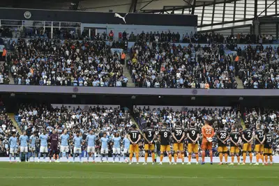 Jugadores del Manchester City, izquierda, y Leeds United de pie durante el himno nacional antes del partido de fútbol de la Premier League inglesa en el estadio Etihad en Manchester, Inglaterra, el sábado 6 de mayo de 2023. (AP Photo/Rui Vieira)
