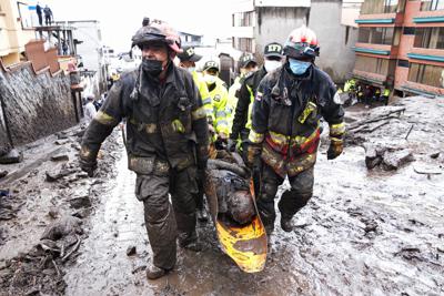 Los equipos de rescate se llevan el cuerpo de una víctima de una inundación repentina provocada por la lluvia que llenó los arroyos cercanos y reventó su mecanismo de contención en el área de La Gasca de Quito, Ecuador, el martes 1 de febrero de 2022. (AP Foto/Dolores Ochoa)