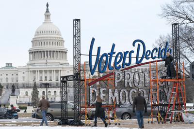 ARCHIVO - Con el Capitolio de fondo, personas pasan cerca de un letrero que dice "Los electores deciden, protejan la democracia", en Washington, el 6 de enero de 2022. (AP Foto/Jacquelyn Martin, Archivo)