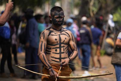 Un manifestante indígena prepara su flecha durante los enfrentamientos entre varios grupos indígenas que protestan contra un proyecto de ley que criminaliza las invasiones de tierras frente al Congreso en Asunción, Paraguay, el miércoles 29 de septiembre de 2021.. (AP Foto/Jorge Saenz)