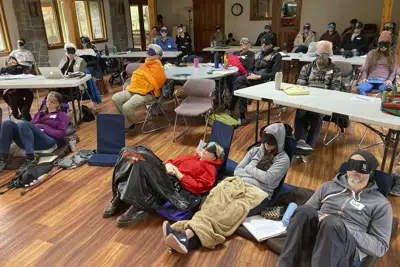 ARCHIVO - Estudiantes facilitadores de psilocibina se sientan con máscaras para los ojos mientras escuchan música durante una actividad experiencial en una sesión de capacitación dirigida por InnerTrek cerca de Damasco, Oregón, el 2 de diciembre de 2022. Los primeros estudiantes se gradúan el viernes 10 de marzo de 2023, marcando un paso importante en el papel pionero de Oregón en el establecimiento de sesiones terapéuticas legales de psilocibina. Los estudiantes fueron entrenados en cómo acompañar a los pacientes que tropiezan con psilocibina. (AP Photo/Andrew Selsky, Archivo)