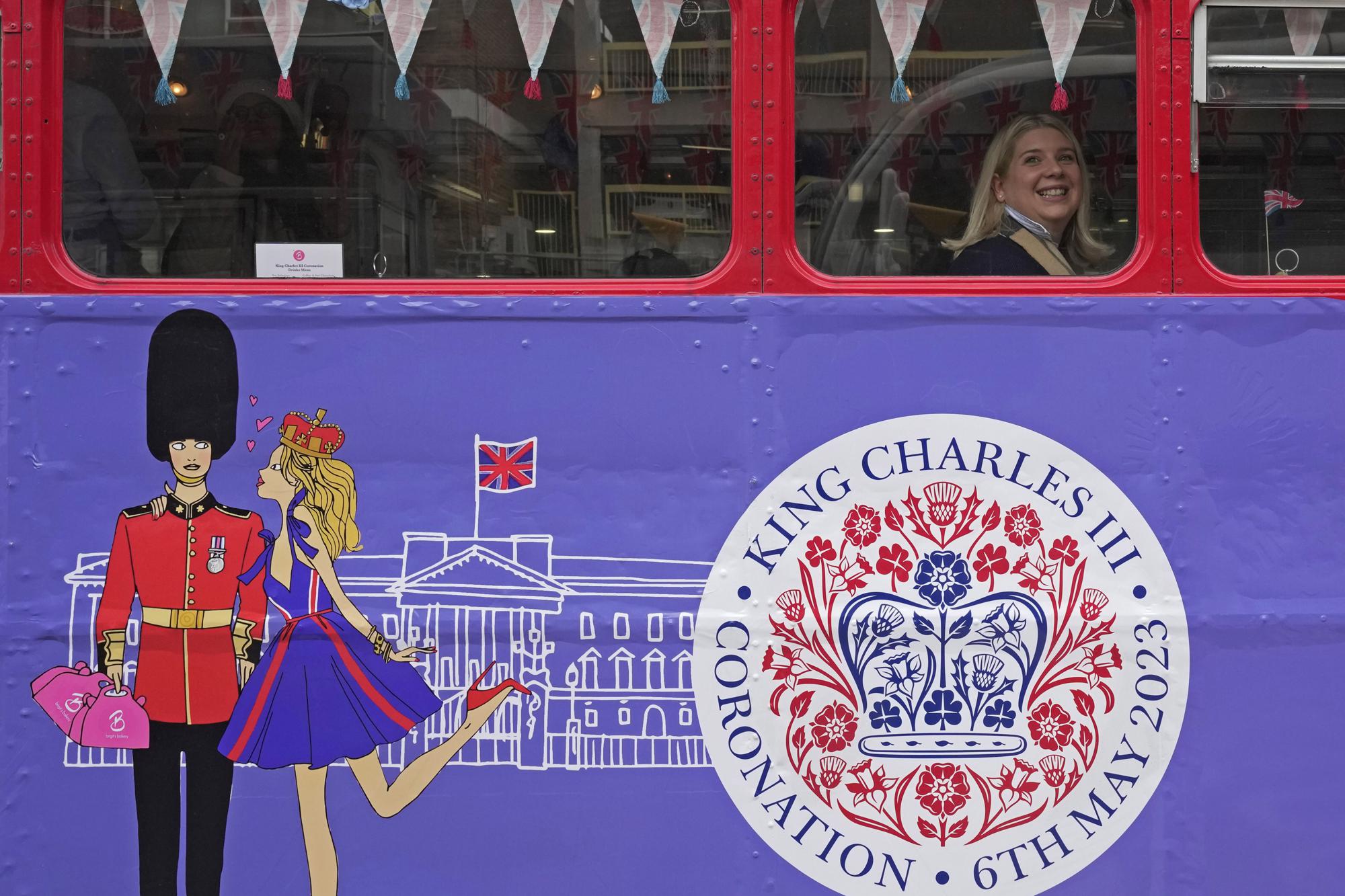 A tourist sits on a Coronation Tour Bus in London, Monday, April 24, 2023. The May 6 coronation is luring royal fans and far-flung visitors fascinated by the ceremonial spectacle — and drama — of the monarchy and eager to experience a piece of British history. Tour companies, shops and restaurants are rolling out the red carpet, whether it's a decked-out bus tour of London's top sights boasting high tea or merchandise running from regal to kitschy. (AP Photo/Kin Cheung)