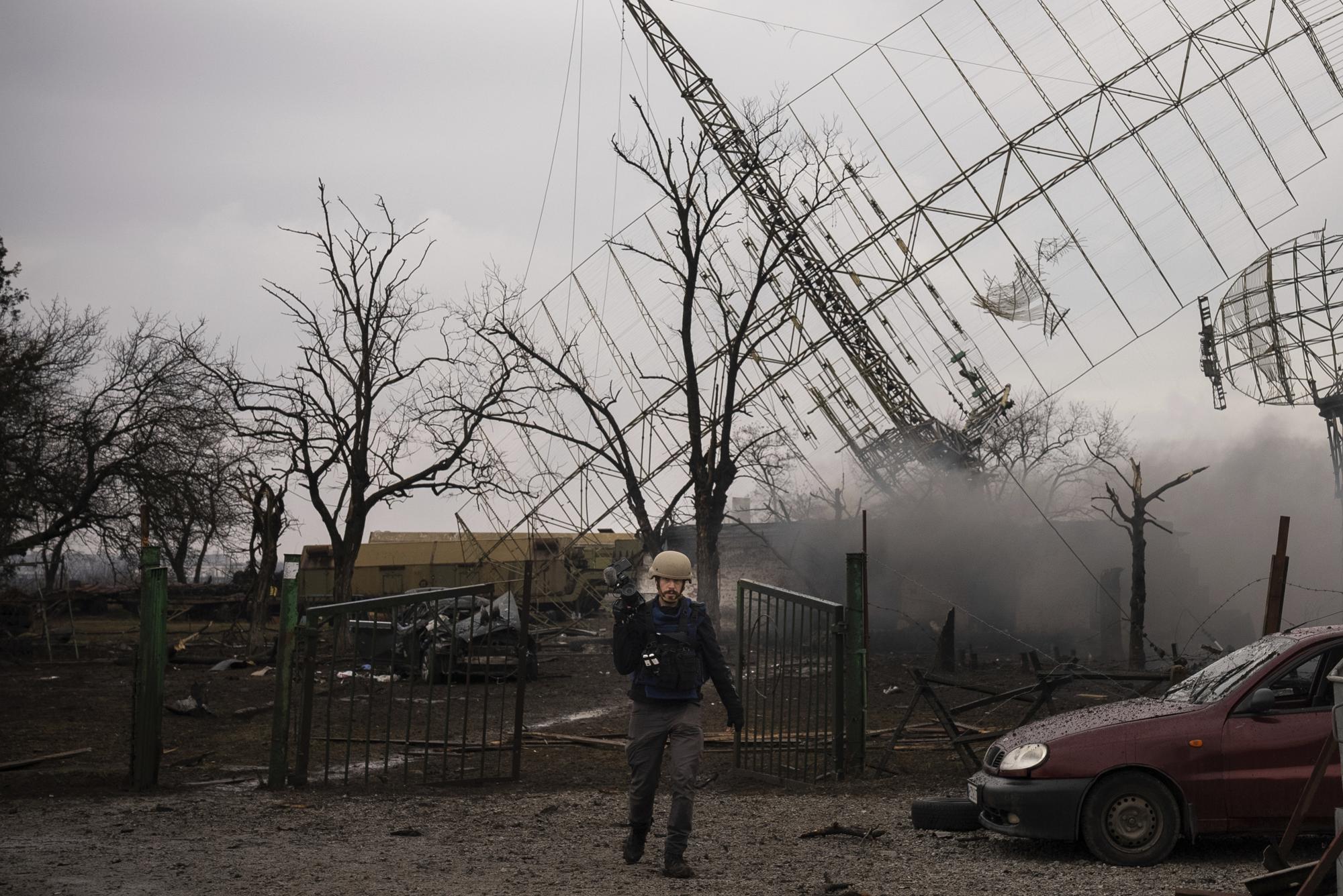 Associated Press videographer Mstyslav Chernov walks amid smoke rising from an air defense base in the aftermath of a Russian strike in Mariupol, Ukraine, Thursday, Feb. 24, 2022. (AP Photo/Evgeniy Maloletka)