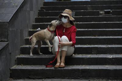 Una mujer, con mascarilla para evitar el contagio de coronavirus, acompañada de su perro durante una visita al parque, el jueves 16 de abril de 2020, en la Ciudad de México. (AP Foto/Marco Ugarte)