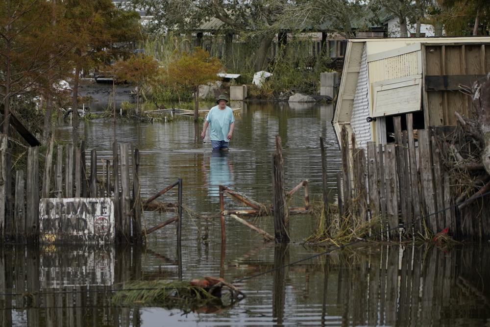 A man walks down a flooded street in the aftermath of Hurricane Ida, Wednesday, Sept. 1, 2021, in Lafitte, La. (AP Photo/John Locher)