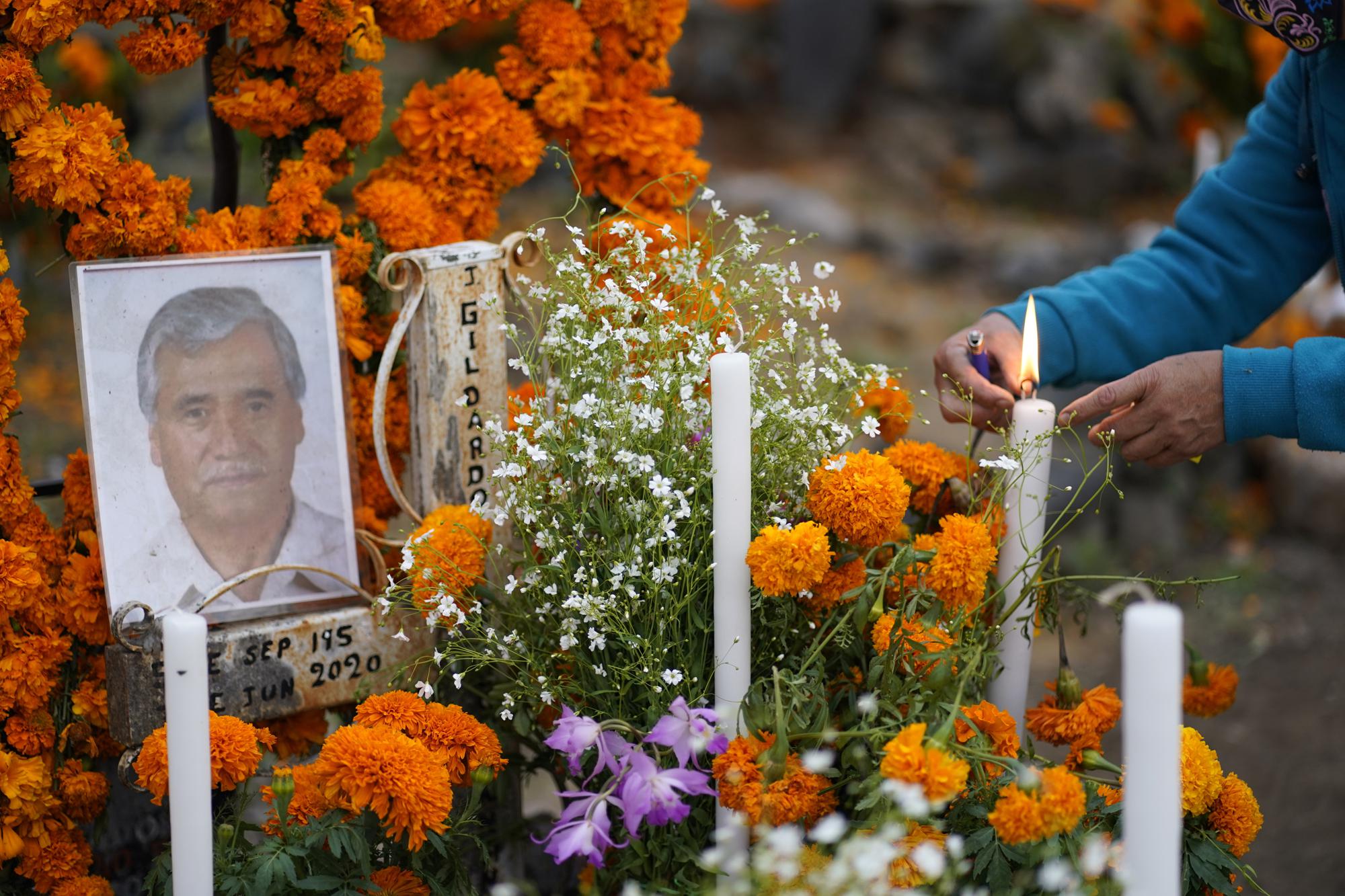 Relatives build an altar as they prepare to spend the night next to the tomb of their loved one during Day of the Dead festivities at the the Arocutin cemetery in Michoacan state, Mexico, Monday, Nov. 1, 2021. In a tradition that coincides with All Saints Day and All Souls Day, families decorate the graves of departed relatives with flowers and candles, and spend the night in the cemetery, eating and drinking as they keep company with their deceased loved ones. (AP Photo/Eduardo Verdugo)