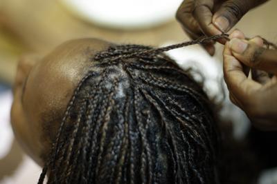 ARCHIVO - Shelly Smith trenza el cabello de una clienta en su salón de belleza Braid Heaven, en Kansas City, Kansas, el 28 de enero de 2020. (AP Foto/Charlie Riedel, Archivo)