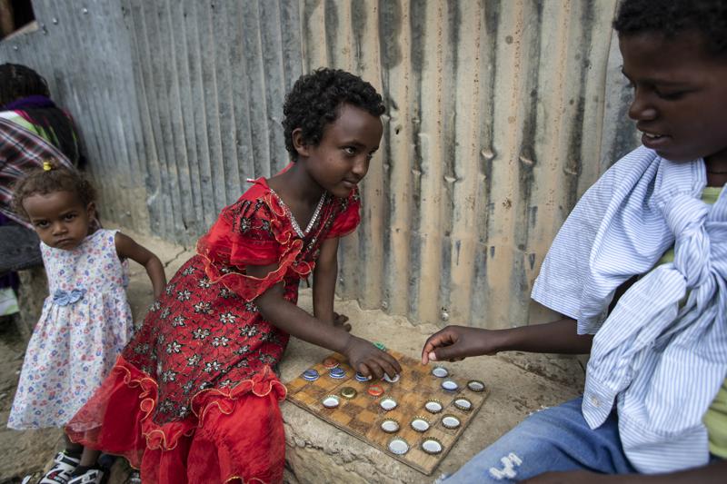 Elena, 7, left, plays a game of checkers using soda bottle tops with friend Hailemariam, 12, at a reception and day center for displaced Tigrayans in Mekele, in the Tigray region of northern Ethiopia, Sunday, May 9, 2021. The Tigray conflict has displaced more than 1 million people, the International Organization for Migration reported in April, and the numbers continue to rise. Some thousands of Eritrean refugees are among the most vulnerable groups in the Tigray conflict and are increasingly caught in the middle of the conflict in Ethiopia’s Tigray region. (AP Photo/Ben Curtis)