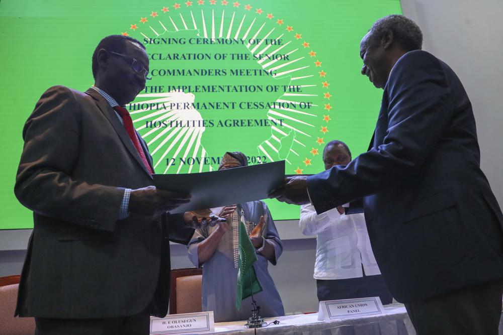 Chief of Staff of Ethiopian Armed Forces Field Marshall Birhanu Jula, left, and Head of the Tigray Forces Lieutenant General Tadesse Werede, right, exchange signed copies of an agreement, at Ethiopian peace talks in Nairobi, Kenya Saturday, Nov. 12, 2022. Top military commanders from Ethiopia and its embattled Tigray region agreed Saturday to allow unhindered humanitarian access to the region and form a joint disarmament committee following last week's truce. (AP Photo/Brian Inganga)