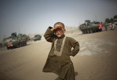 ARCHIVO - En esta foto de archivo del 6 de agosto de 2009, un niño observa a los vehículos militares de la 5ta Brigada Striker que cruzan su comunidad en las afueras de Spin Boldak, a unos 100 kilómetros (63 millas) al sureste de Kandahar, Afganistán. (AP Foto/Emilio Morenatti, Archivo)