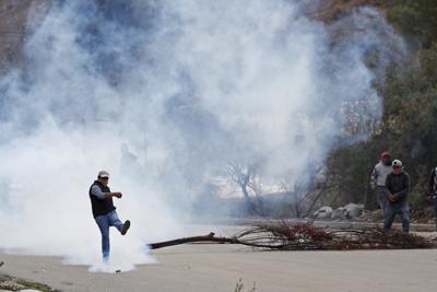 ARCHIVO - En esta foto de archivo del 11 de noviembre de 2019, un hombre patea una granada de gas lacrimógeno en choques entre la policía y partidarios del expresidente Evo Morales en La Paz, Bolivia. Un ex alto funcionario boliviano, Sergio Méndez, fue arrestado y acusado de solicitar sobornos a un grupo de empresarios en Florida que vendían gases lacrimógenos a precios inflados al gobierno derechista de la presidenta interina Jeanine Anez. (AP Foto/Juan Karita, File)