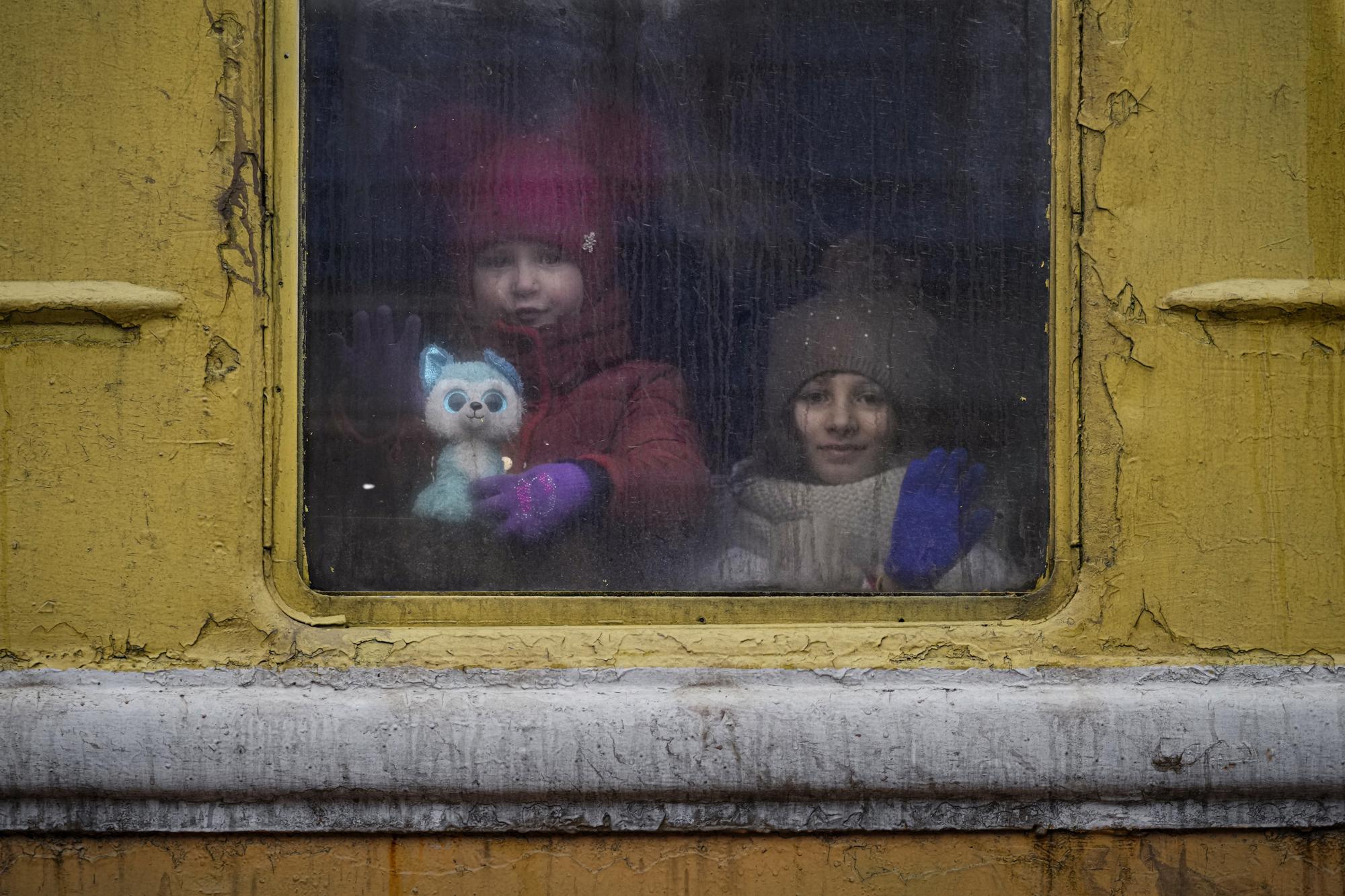 Children look out the window of an unheated Lviv bound train, in Kyiv, Ukraine, Thursday, March 3, 2022. (AP Photo/Vadim Ghirda)