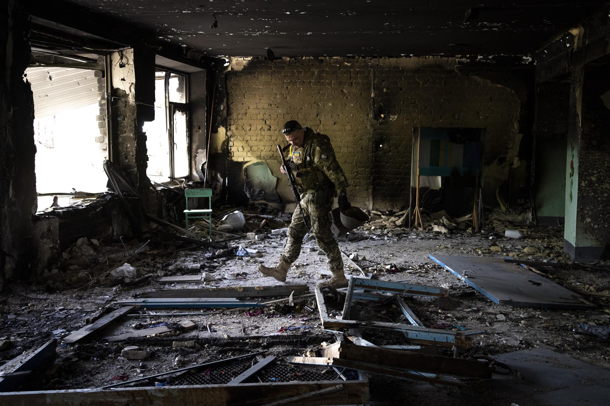 Un militar ucraniano inspecciona una escuela dañada durante una batalla entre las fuerzas rusas y ucranianas en la aldea de Vilkhivka, en las afueras de Kharkiv, en el este de Ucrania, el viernes 20 de mayo de 2022. (Foto AP/Bernat Armangue)