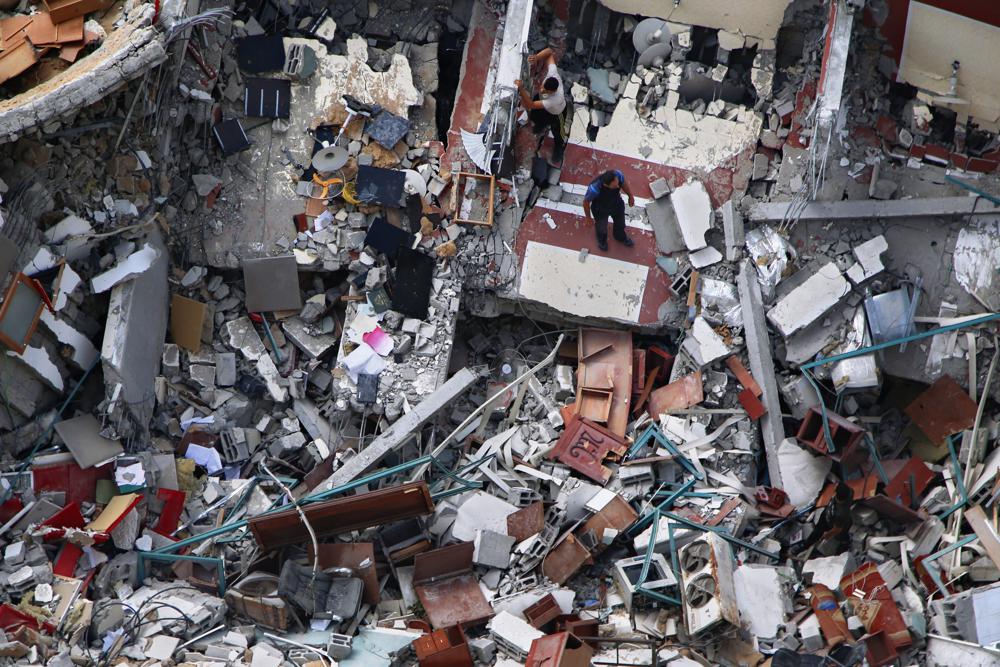 Palestinians inspect the destroyed building housing the offices of The Associated Press and other media, after it was hit last week by Israeli airstrike, in Gaza City, Friday, May 21, 2021. A cease-fire took effect early Friday after 11 days of heavy fighting between Israel and Gaza's militant Hamas rulers that was ignited by protests and clashes in Jerusalem. (AP Photo/Hatem Moussa)