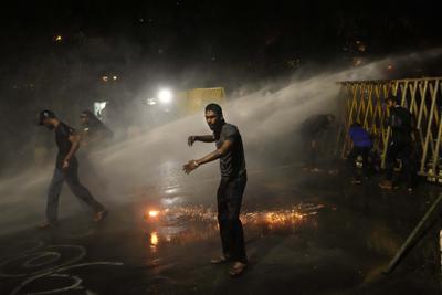 Manifestantes corren para cubrirse mientras la policía dispara proyectiles de gas lacrimógeno cerca de la residencia oficial del presidente en Colombo, Sri Lanka, el sábado 28 de mayo de 2022. La policía disparó gases lacrimógenos y cañones de agua contra los manifestantes que marcharon hacia la residencia con barricadas del presidente Gotabaya Rajapaksa exigiendo su renuncia. (AP Foto/Eranga Jayawardena)