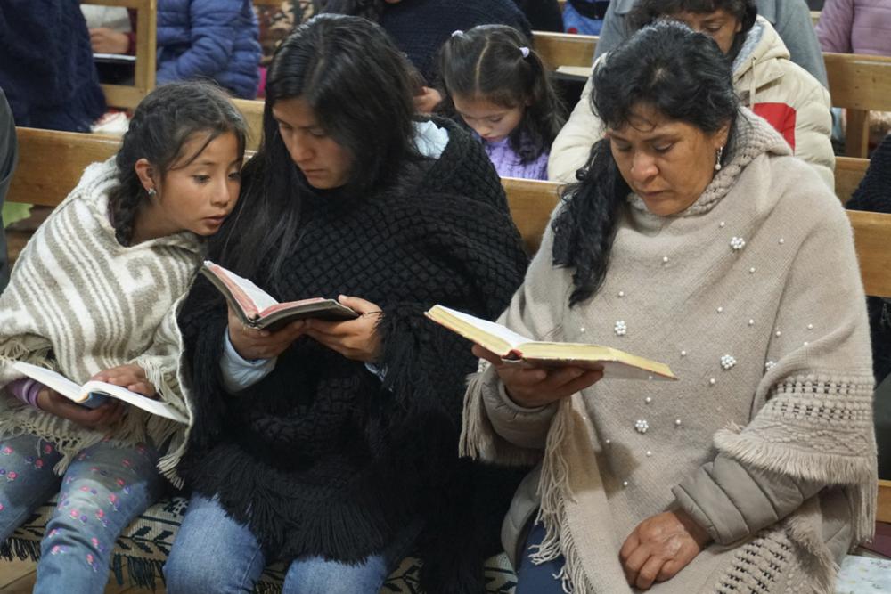 La futura primera dama de Perú, Lilia Paredes, derecha, lee la Biblia junto a su hermana menor Yenifer y la hija de ésta, Alondra, de 9 años, durante una ceremonia religiosa el jueves 22 de julio de 2021 a la que fueron invitados los vecinos para despedirse de la familia antes de que parta hacia Lima, en la iglesia del Nazareno, en Chugur, Perú. (AP Foto/Franklin Briceño)