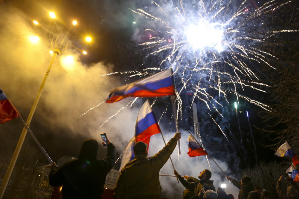 People wave Russian national flags celebrating the recognizing the independence in the center of Donetsk, the territory controlled by pro-Russian militants, eastern Ukraine, late Monday, Feb. 21, 2022. In a fast-moving political theater, Russian President Vladimir Putin has moved quickly to recognize the independence of separatist regions in eastern Ukraine in a show of defiance against the West amid fears of Russian invasion in Ukraine. (AP Photo/Alexei Alexandrov)