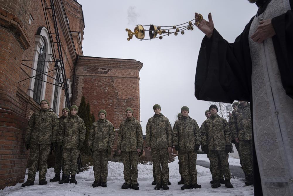 An Orthodox priest blesses Ukrainian Military Air Force University cadets after a monthly memorial service for soldiers who were killed during the fighting against Russia-backed separatists in eastern Ukraine, in Kharkiv, Ukraine, Thursday, Feb. 3, 2022. Russia maintains it has no intention to attack its neighbor, but demands that NATO won't expand to Ukraine and other ex-Soviet nations or deploy weapons there. It also wants the alliance to roll back its deployments to Eastern Europe. (AP Photo/Evgeniy Maloletka)