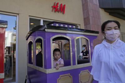 Un niño en un trencito pasa frente a una tienda H&M en Beijing, jueves 3 de junio de 2021. El gobierno chino ha acusado a H&M, Nike, Zara y otras marcas de importar ropa y otras mercaderías para niños de mala calidad. (AP Foto/Ng Han Guan)