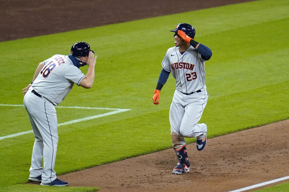 Michael Brantley (23) de los Astros de Houston comparte un saludo con el entrenador de tercera base Omar López mientras Brantley se dirige a casa después de conectar un jonrón en solitario contra los Marineros de Seattle durante la sexta entrada de un juego de béisbol el martes 22 de septiembre de 2020.