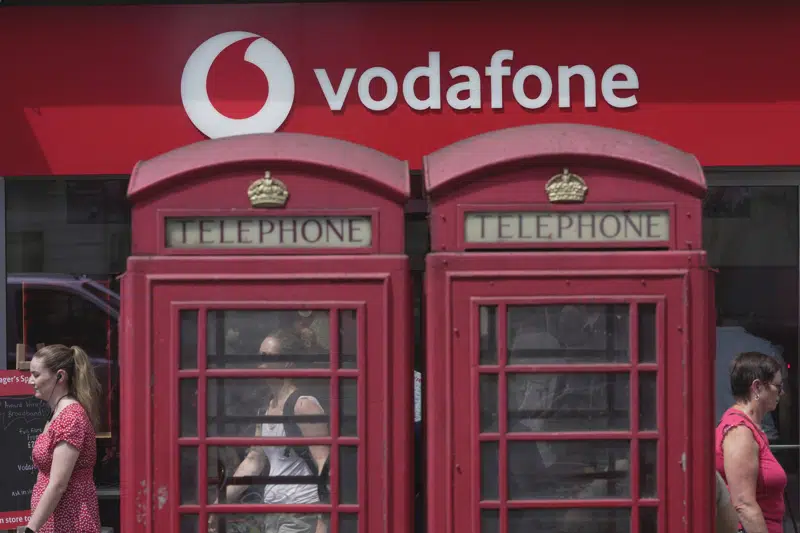 People walk past a Vodafone store in London, Wednesday, June 14, 2023. Vodafone and Three, which is owned by Hong Kong's CK Hutchison agreed Wednesday to merge their U.K. businesses in order to capitalize on the rollout of the next generation of wireless technology. (AP Photo/Kin Cheung)