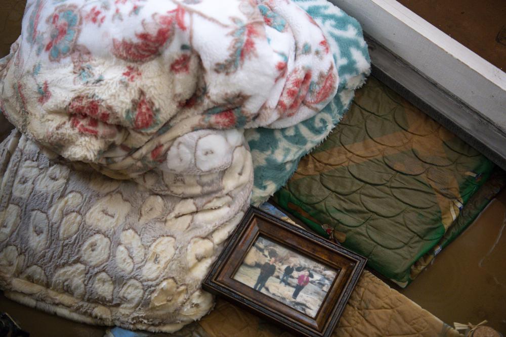 Ruined and muddied blankets sit on the ground with a photo frame in the spare bedroom of Joy and Gary Rhodes' home after their home flooded following heavy rainfall on Saturday, Aug. 21, 2021, in Dickson, Tenn. (Josie Norris/The Tennessean via AP)