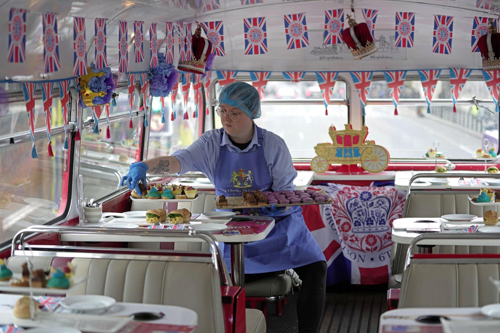 A staff member prepares afternoon tea for the new Coronation Tour Bus route, in London, Monday, April 24, 2023. The May 6 coronation is luring royal fans and far-flung visitors fascinated by the ceremonial spectacle — and drama — of the monarchy and eager to experience a piece of British history. Tour companies, shops and restaurants are rolling out the red carpet, whether it's a decked-out bus tour of London's top sights boasting high tea or merchandise running from regal to kitschy. (AP Photo/Kin Cheung)