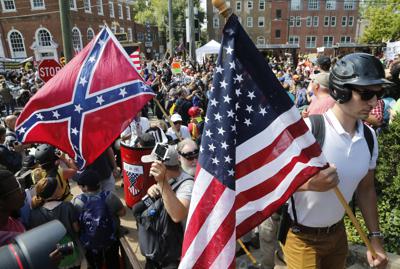ARCHIVO - Manifestantes nacionalistas blancos entran al parque Lee rodeados de contramanifestantes en Charlottesville, Virginia, el sábado 12 de agosto de 2017. En su informe anual, publicado el miércoles 9 de marzo de 2022, el Southern Poverty Law Center dijo que identificó 733 grupos de odio activos en 2021, por debajo de los 838 contabilizados en 2020 y los 940 contabilizados en 2019. Los grupos de odio habían subido a un máximo histórico de 1.021 en 2018, dijo el centro de leyes, que rastrea el racismo, la xenofobia y las milicias de extrema derecha. (AP Photo/Steve Helber, Archivo)