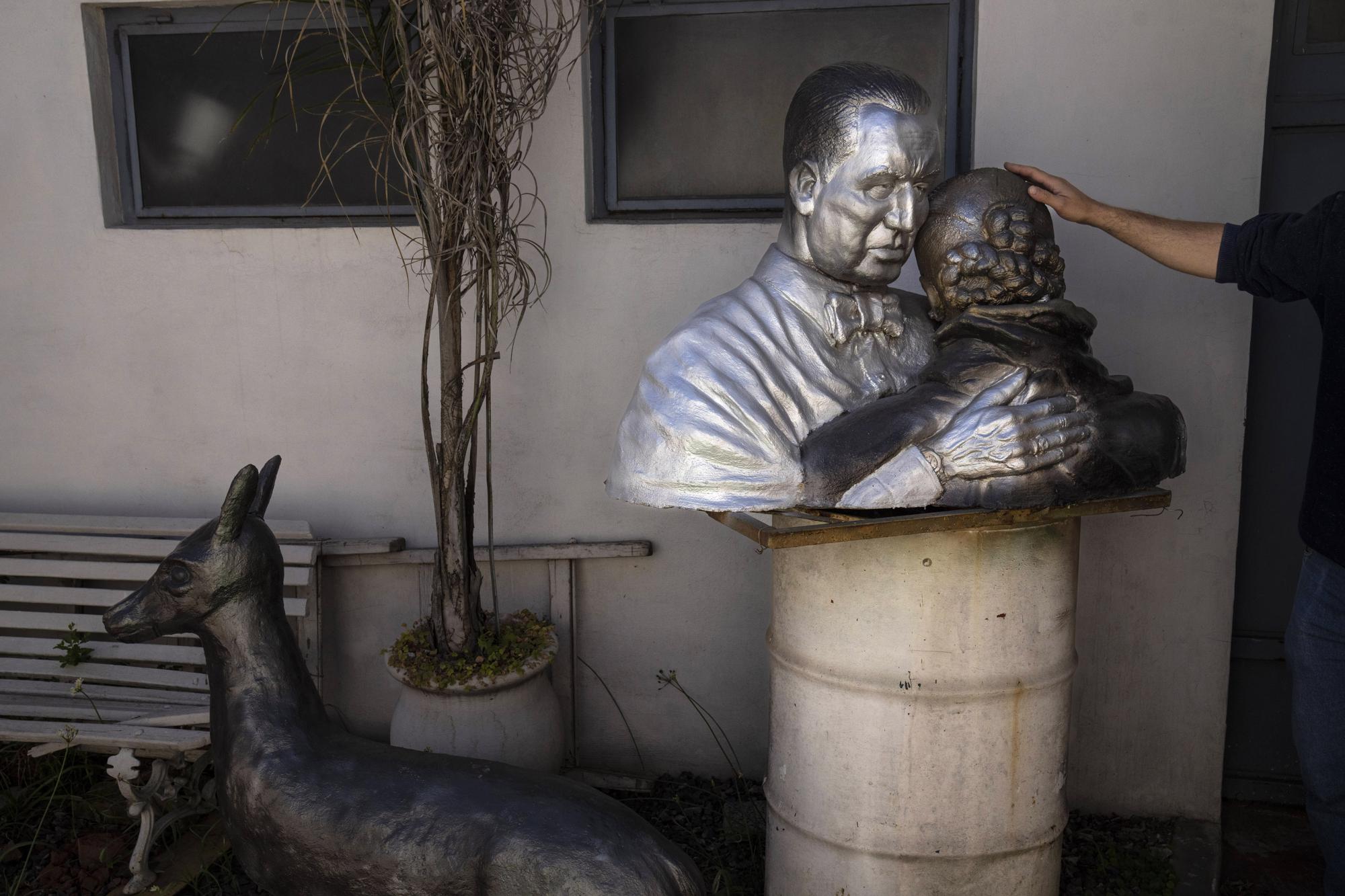 Un busto que representa a Juan Domingo Perón, tres veces presidente de Argentina, y su esposa Eva "Evita" Duarte, abrazados, reposa sobre un trozo de madera encima de un tonel en el patio de la casa familiar del artista Héctor Duarte en San Miguel, Argentina, martes 1 de noviembre de 2022.  (AP Foto/Rodrigo Abd)