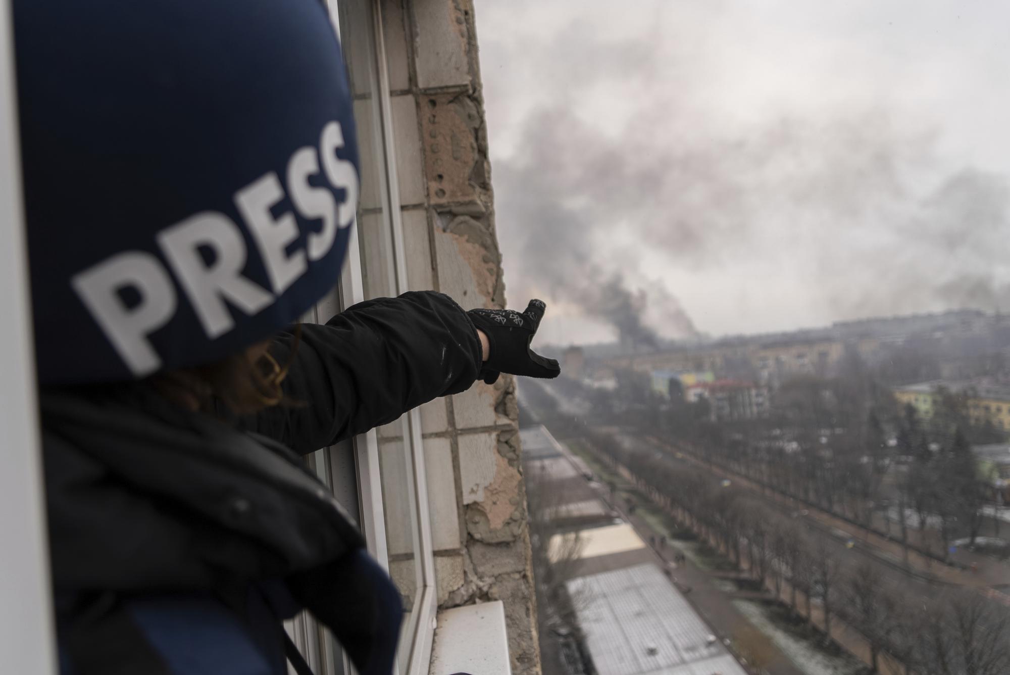Associated Press photographer Evgeniy Maloletka points at the smoke rising after an airstrike on a maternity hospital, in Mariupol, Ukraine, Wednesday, March 9, 2022. (AP Photo/Mstyslav Chernov)