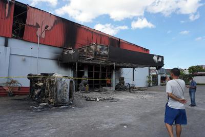 Un hombre observa los restos calcinados de un club nocturno que se incendio después de que dos grupos se enfrenaron dentro del lugar, el martes 25 de enero de 2022, en la ciudad de Sorong, en la provincia de Papúa Occidental, Indonesia. (AP Foto)