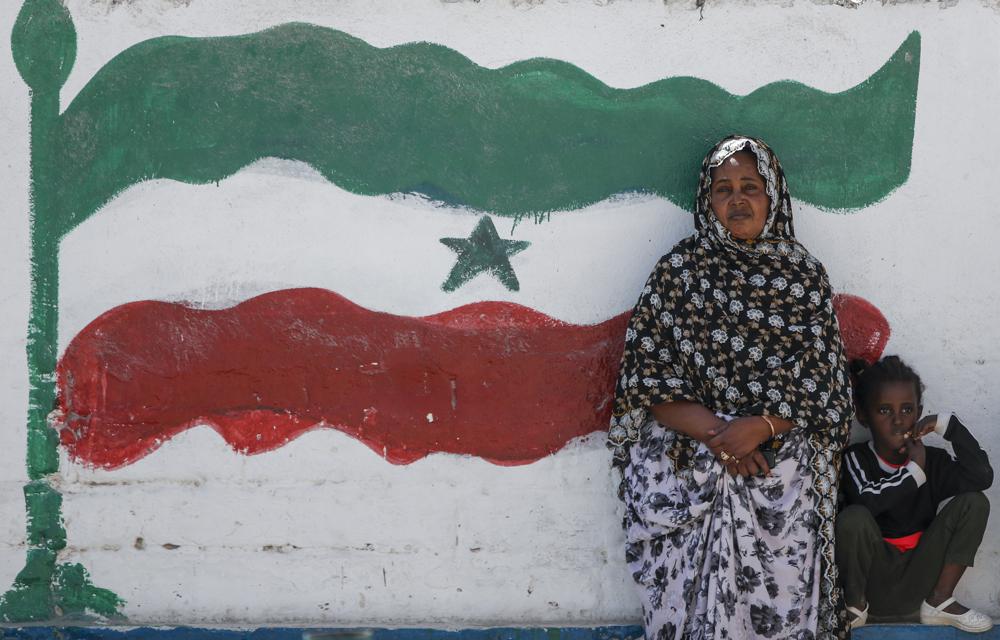 FILE - A woman and child relax next to a mural of Somaliland's flag, in Hargeisa, Somaliland, a semi-autonomous breakaway region of Somalia, on Feb. 9, 2022. The leader of Somaliland urged the international community on Monday, March 14 to recognize his territory's quest for independence, saying negotiations with Somalia had failed. (AP Photo/Brian Inganga, File)