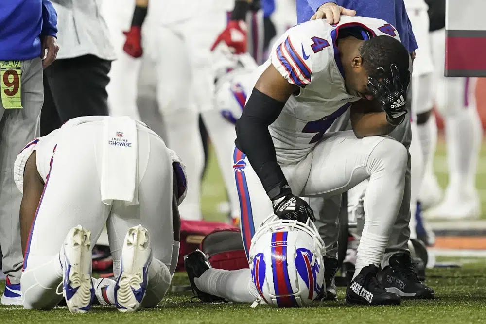 Buffalo Bills players and staff pray for Buffalo Bills' Damar Hamlin during the first half of an NFL football game against the Cincinnati Bengals, Monday, Jan. 2, 2023, in Cincinnati. The game has been postponed after Buffalo Bills' Damar Hamlin collapsed, NFL Commissioner Roger Goodell announced. (AP Photo/Joshua A. Bickel)