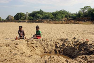 En esta imagen de archivo, tomada el 11 de noviembre de 2020, dos niños sentados junto a un agujero con agua en el lecho de un río seco en Fenoaivo, una aldea remota de Madagascar. (AP Foto/Laetitia Bezain, archivo)