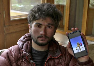 El paquistaní Shehroz Kashif, de 19 años, muestra una fotografía en su teléfono en la que aparece sosteniendo una bandera de Pakistán en la cima de la montaña K2, durante una entrevista con The Associated Press en Skardu, en el norte de Pakistán, el domingo 1 de agosto de 2021. (AP Foto/M.H. Balti)