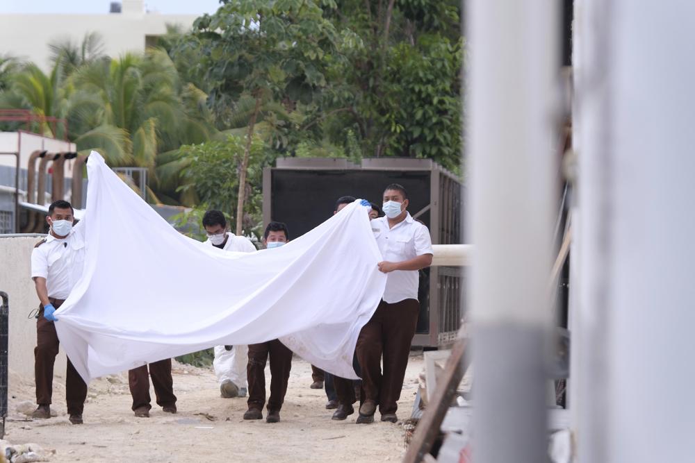 La policía sostiene una sábana en un intento de bloquear a los espectadores después de un enfrentamiento armado cerca de un hotel cerca de Puerto Morelos, México, el jueves 4 de noviembre de 2021. (AP Foto / Karim Torres)