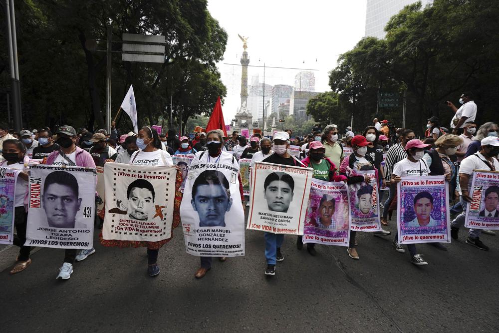 Supporters and relatives of the 43 missing university students hold placards with photos of their loved ones as they march on the seventh anniversary of their disappearance, in Mexico City, Sunday, Sept. 26, 2021. Relatives continue to demand justice for the Ayotzinapa students who were allegedly taken from the buses by the local police and handed over to a gang of drug traffickers. (AP Photo/Marco Ugarte)