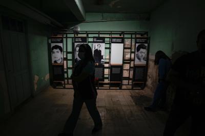 Una enfermera camina frente a imágenes de personas que fueron torturadas y asesinadas durante la dictadura chilena de 1973 a 1990 en el sótano del Hospital Metropolitano, que alguna vez fue el sitio de un centro clandestino de detención, en Santiago de Chile, el jueves 27 de octubre de 2022. (AP Foto/Esteban Felix)