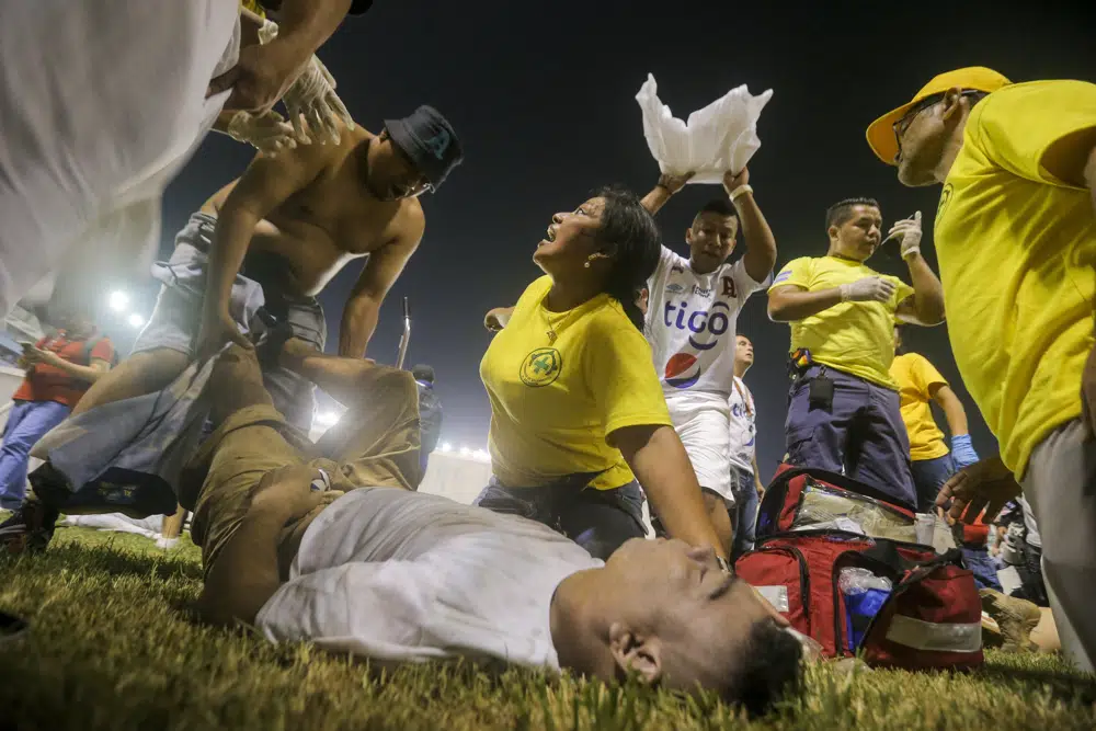 Aficionados al fútbol atienden en la cancha a los heridos por una estampida humana en el estadio Cuscatlán de San Salvador, el sábado 20 de mayo de 2023. (AP Foto/Milton Flores)